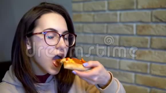 一个年轻的女人正在吃一片比萨饼女人坐在餐馆里吃披萨特写视频的预览图