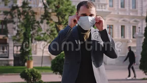 在街中央一个男人拿起他的保护面具把他的脸同时直视着相机这是一个视频的预览图