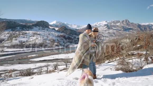 一对年轻漂亮的夫妇带着可爱的小狗在雪山上视频的预览图