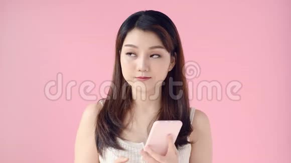 技术通讯和人的概念亚洲女性拨打电话和拨打粉色背景的智能手机视频的预览图
