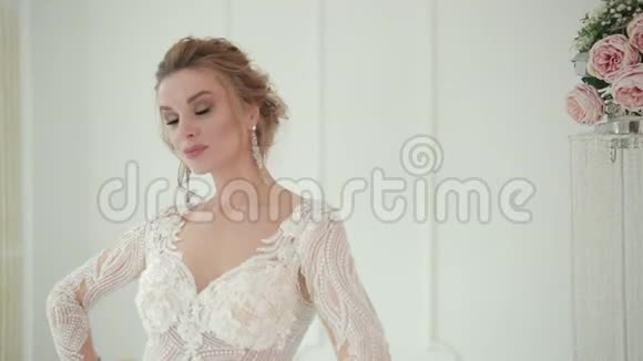 身着白色礼服的金发新娘摆姿势拍照用手指触摸她的脸视频的预览图