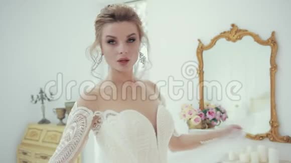 年轻的金发新娘穿着白色婚纱在镜头前摆姿势转身视频的预览图