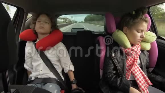 带旅行枕头的兄妹在旅行时睡在车后座视频的预览图