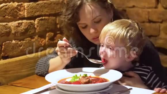 年轻女子带着小男孩在餐厅酒吧吃新鲜汤视频的预览图