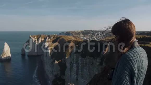 快乐女游客看着令人惊叹的Etretat白海岩风景独自冥想头发在风中吹起视频的预览图