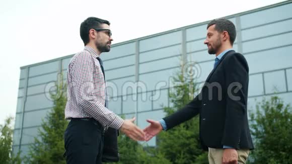 商业伙伴男人握手在城市里站在户外做交易视频的预览图