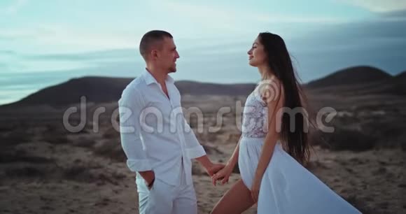 美丽的男人和他的女人带着巨大的微笑站在镜头前在令人惊叹的风景中视频的预览图