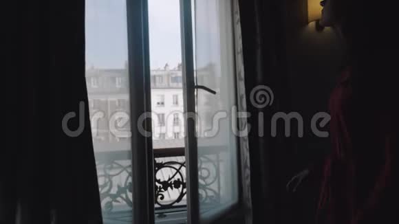 剪影拍摄的快乐年轻的当地妇女走到阳台窗口享受阳光埃菲尔铁塔景的慢动作视频的预览图