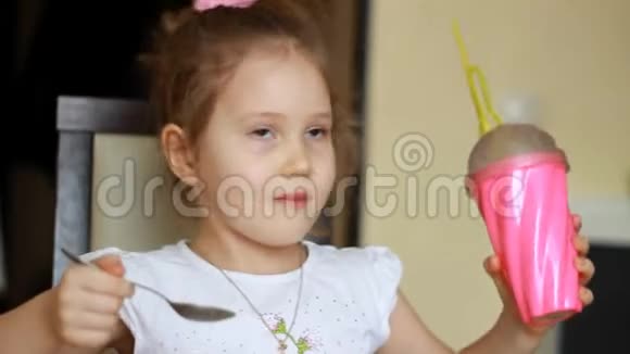 女婴喝着粉红色玻璃杯里吸管里的饮料视频的预览图