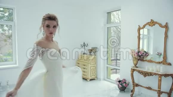 年轻的金发新娘穿着白色婚纱在镜头前摆姿势转身视频的预览图