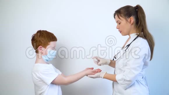 一名女医生用消毒喷雾消毒小男孩的手柯维德19保护停止冠状病毒视频的预览图