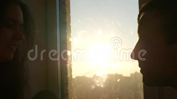 一对相爱的夫妇在日落时在窗前接吻动作缓慢视频的预览图