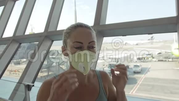女子白种人在机场头上戴着防护医疗面罩飞机背景冠状病毒视频的预览图