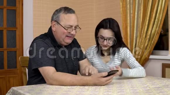 女儿教父亲如何使用电话一个年轻的女人告诉她的老父亲在哪里点击智能手机那个人视频的预览图