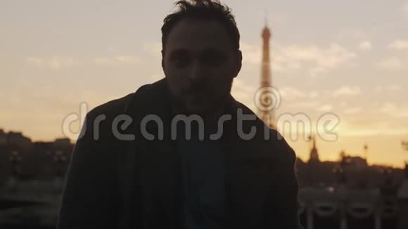 大气暗日落画像浪漫微笑的欧洲男人看镜头在巴黎埃菲尔铁塔慢动作视频的预览图