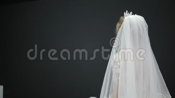 年轻美丽的新娘穿着白色婚纱戴着面纱坐在床栏杆上视频的预览图