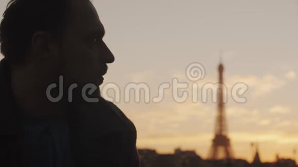 近距离描绘了一个思想冷静的白人年轻人看着镜头在巴黎埃菲尔铁塔天景慢镜头视频的预览图