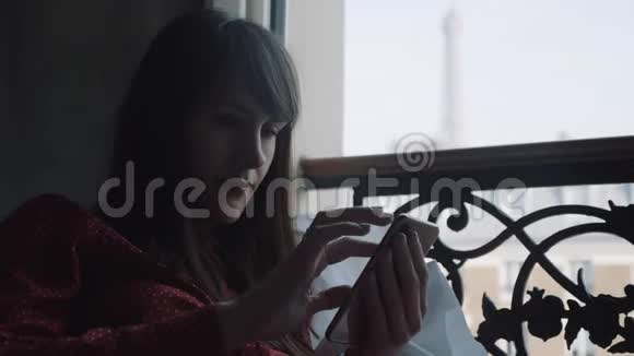 在法国阳台上使用智能手机应用程序在埃菲尔铁塔上观看度假慢动作特写漂亮的黑发女人视频的预览图