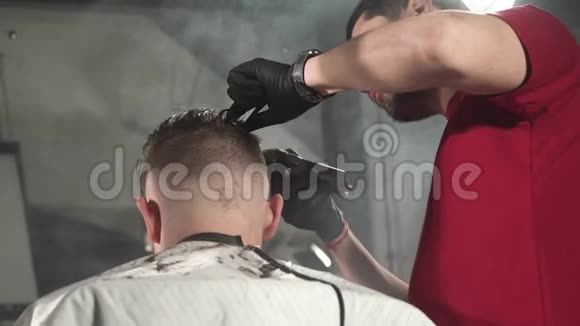 在理发店里红色t恤和黑色手套的理发师的后视角使顾客刮胡子视频的预览图