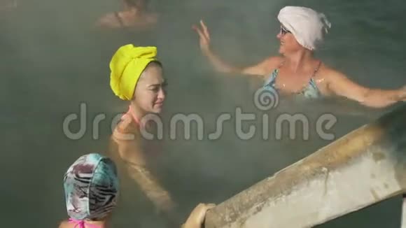 小女孩妈妈和奶奶在室外的传统水疗中心在热水盐水中游泳软软的视频的预览图