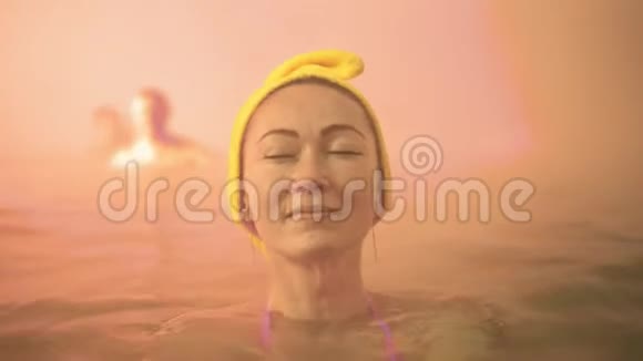 在传统的室外水疗中心用柔软的粉红色魔法在热盐水矿物浴中游泳把白种人的女人关起来视频的预览图
