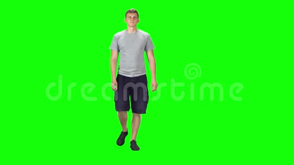 穿着灰色T恤短裤和运动鞋的年轻人穿着绿色背景视频的预览图