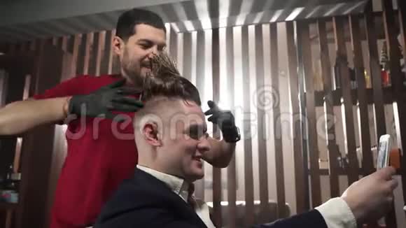理发店的博客理发师或理发师穿着红色T恤和黑色手套摆着顾客莫霍克在那之后视频的预览图