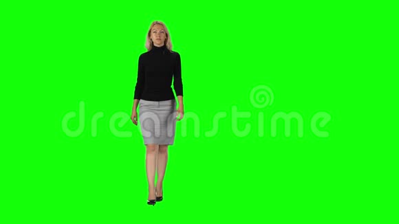 金发女孩穿黑色高领毛衣灰色裙子和高跟鞋与绿色屏幕视频的预览图