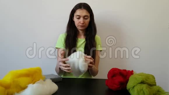 一个黑发女人在家做针线活一个严肃的女孩创造了一个羊毛玩具从羊毛中干毡有趣的爱好视频的预览图