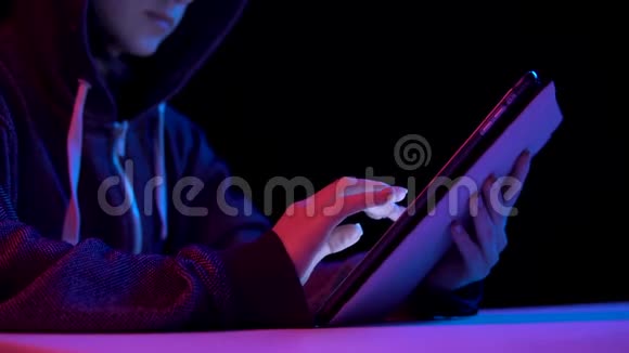 戴着平板电脑的女青年黑客通过平板电脑进行黑客攻击蓝色和红色的光落在一个女人身上视频的预览图