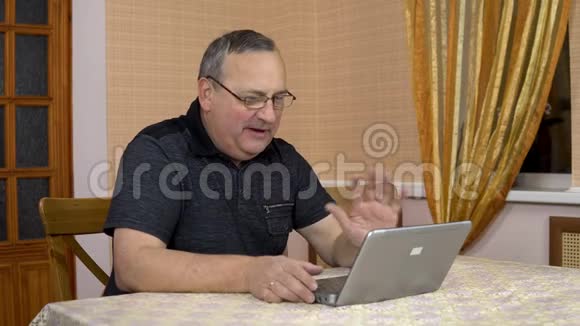 一个男人通过笔记本电脑通过视频与朋友交流一位老人在看手提电脑时交流A视频的预览图