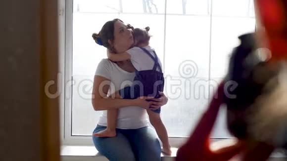母亲和女儿穿着白色T恤衫坐在工作室的窗户上视频的预览图