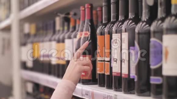 年轻女性在超市顾客选择葡萄酒选择酒类品牌销售视频的预览图