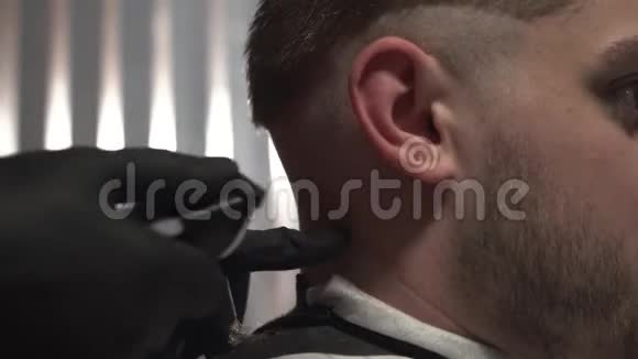 特写镜头剪子剃掉理发店里一个男人的后脑勺戴黑色手套的理发师视频的预览图
