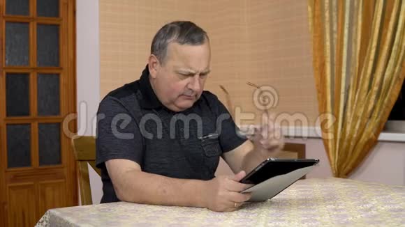男人第一次使用平板电脑一位老人使用平板电脑有困难舒适的房间里的男人视频的预览图
