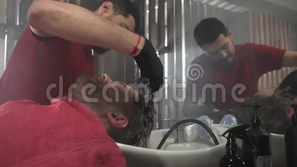 理发店给客户洗头戴黑色手套和红色T恤的理发师视频的预览图