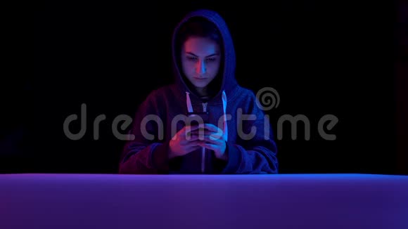 戴着智能手机的女青年黑客通过电话攻击蓝色和红色的光落在一个女人身上视频的预览图