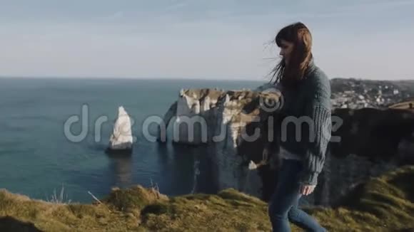 美丽兴奋的女游客沿着华丽的Etretat海洋全景和岩石随风飘动视频的预览图