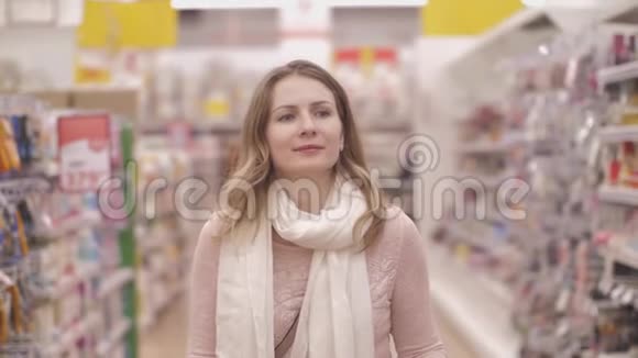 微笑的年轻女顾客在超市购物车旁散步顾客感到高兴视频的预览图