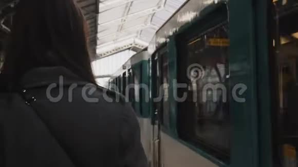 后景年轻女子沿着到达的地铁列车在巴黎火车站站台看着正确的慢动作视频的预览图