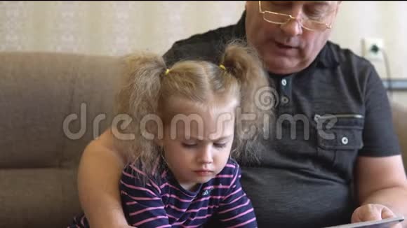 孙女正在和祖父一起读一本书女孩皱着眉头看着那本书仔细地听着祖父的话视频的预览图