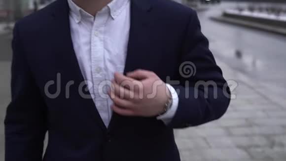 穿着白色衬衫的商人走在街上从蓝色夹克的胸袋里拿出电话视频的预览图