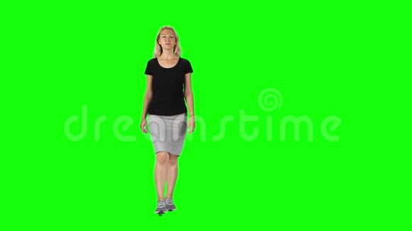 金发女孩穿着黑色T恤灰色裙子和运动鞋靠在绿色的屏幕上视频的预览图