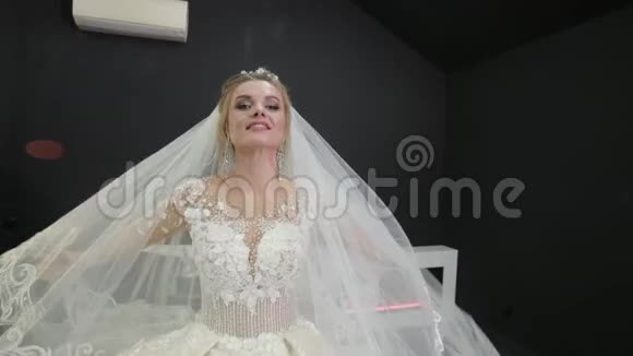 年轻的新娘穿着白色的婚纱坐在床上玩着面纱视频的预览图