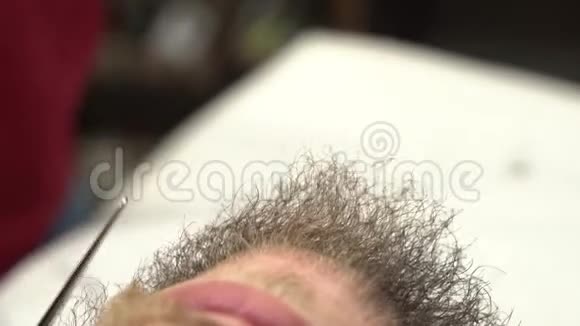 为留胡子的家伙用剪刀合上剪胡子的镜头女人在理发店为男人修剪胡须视频的预览图