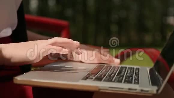 女孩的手在笔记本电脑上特写女孩打字在户外使用笔记本电脑视频的预览图