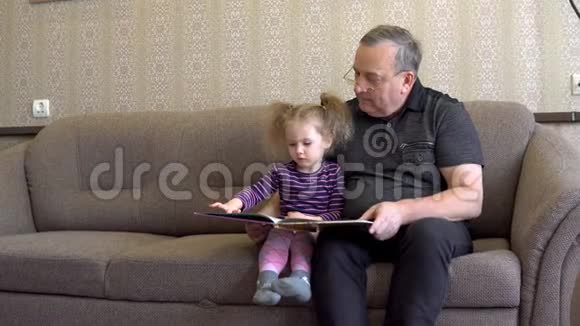孙女正在和祖父一起读一本书女孩皱着眉头看着书仔细地听着祖父的话视频的预览图