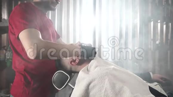 戴黑色手套的理发师用特殊的奶油做胡须按摩一个穿红色T恤的理发师准备剪一个视频的预览图