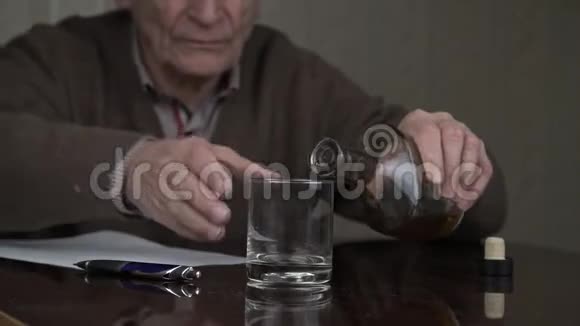 老人用颤抖的双手将白兰地倒入玻璃杯中视频的预览图