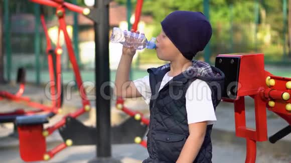 小男孩在室外公共健身器材附近饮水儿童运动视频的预览图